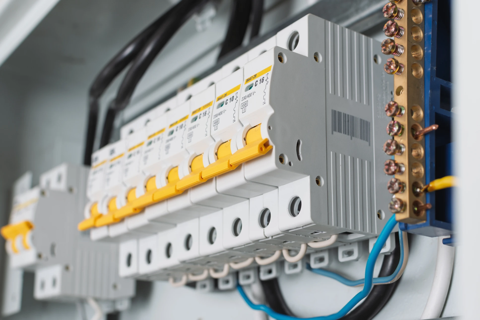 Photographie réaliste d'un électricien professionnel en train d'installer ou de travailler sur une installation électrique dans un intérieur résidentiel en rénovation. L'électricien porte des équipements de sécurité appropriés et travaille sur des éléments électriques visibles (câblage, tableaux électriques, prises, ou installation de fils). L'arrière-plan montre un chantier de rénovation intérieure avec murs en cours de finition, mettant en avant à la fois le métier principal d'électricien et le contexte de rénovation complète de la maison.