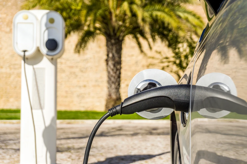 Électricien qualifié IRVE en tenue professionnelle installant ou contrôlant une borne de recharge murale dans un environnement résidentiel ou professionnel, mettant en avant les gestes techniques précis et la rigueur du travail électrique. La borne doit être clairement visible et l'environnement professionnel et conforme.