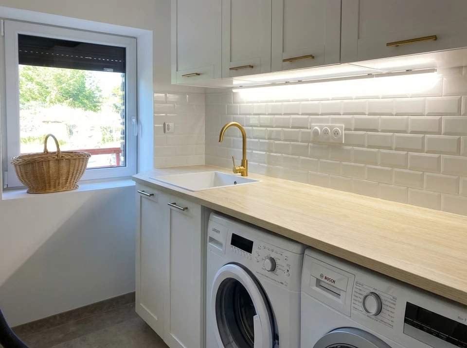 Photo réaliste d'un chantier de rénovation intérieure montrant un artisan en tenue professionnelle travaillant dans une pièce en cours de transformation. L'image doit montrer clairement plusieurs étapes/domaines de travail : une zone avec des installations électriques visibles (fils, gaines, prises), une autre avec des travaux de plomberie (tuyauterie), du placo ou des cloisons partiellement installées, et des matériaux de carrelage ou de finition visibles. L'artisan doit être au centre de l'image, encadré par ces différents corps de métier, illustrant sa polyvalence et sa capacité à coordonner des travaux d'intérieur variés.
